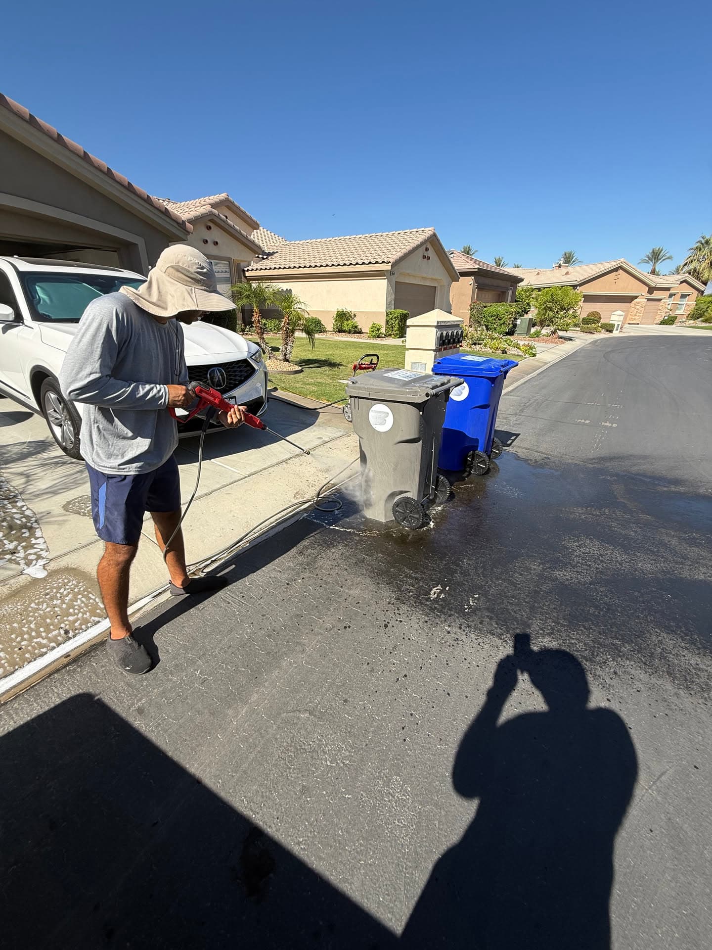 Diego washing a trash bin curbside in the Coachella Valley sun
